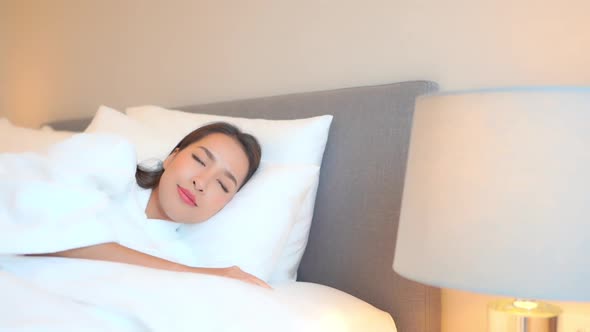 Asian woman relax on bed in bedroom interior