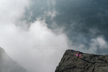 raction in Ryfylke, towers over the Lysefjord. Girl on a rock with the flag of Norway
