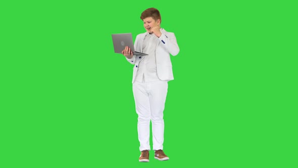 Boy Standing Using Laptop And Making Win Gesture on a Green Screen, Chroma Key.