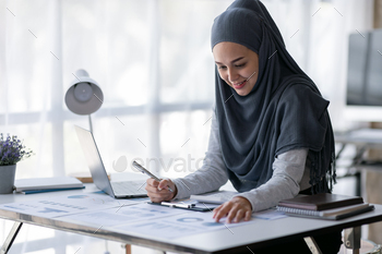 riting make note with calculate doing math finance on an office desk. Woman working at office with laptop and tax, accounting, documents on desk