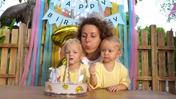 Single Mom Helps Her Twin Toddlers to Blow Candles Out at Second Birthday Party in the Garden