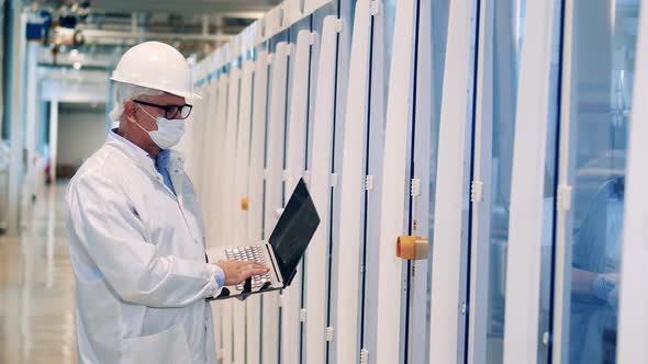 Male Specialist with a Laptop is Inspecting Factory Cabinets