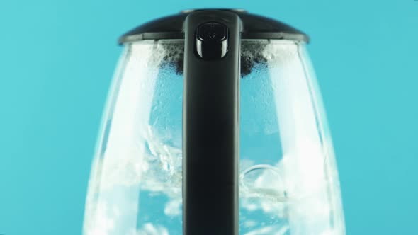 Electric Kettle with Transparent Walls. Boiling. Blue Background. Close-up