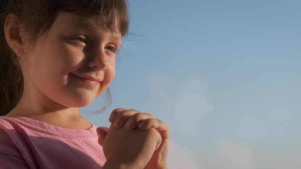 Happy child prays at the window. 