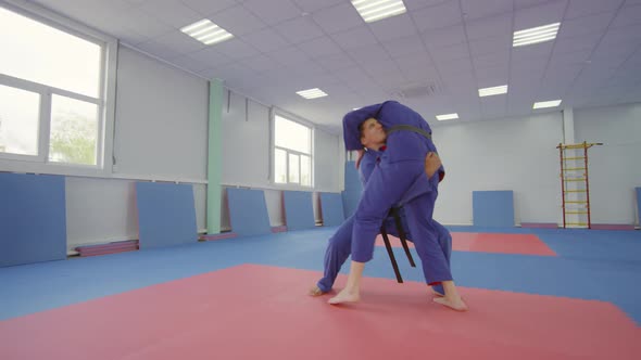 Male Jujutsu Athlete Throwing Female Partner on Mat while Sparring in Gym