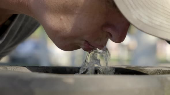 Woman drinks spring water from city fountain