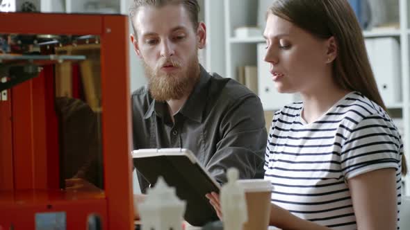 Young Male and Female Designers Working with 3D Printer