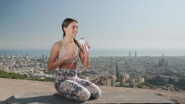 Woman Opening Bottle with Water Outdoors. Girl Drinking Water at Viewpoint