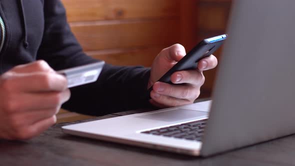 Businessman in a Black Hoodie Making Online Payment with Credit Card and Smartphone Online Shopping