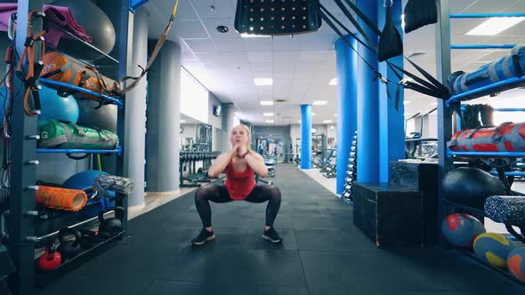 Young woman is squatting in the gym.