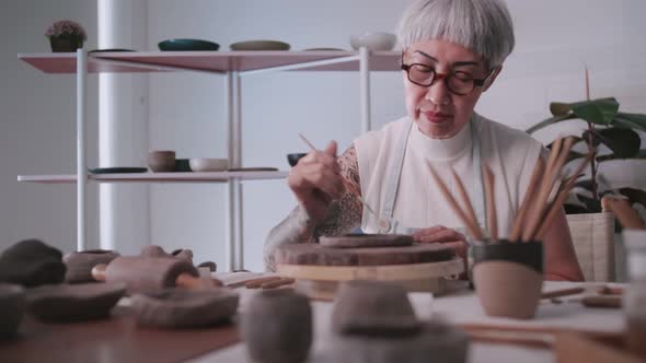 Asian elderly woman enjoying pottery work at home.