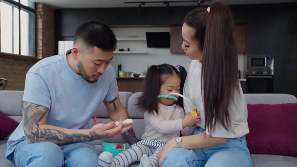 Joyful Asian Parents and Daughter Playing Doctor Game