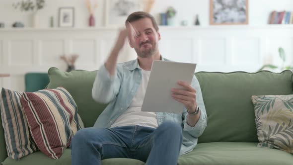 Young Man Enjoying Success While Reading Documents on Sofa