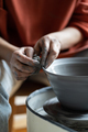 Female potter shaping wet clay on turning wheel into kitchenware in pottery studio - PhotoDune Item for Sale