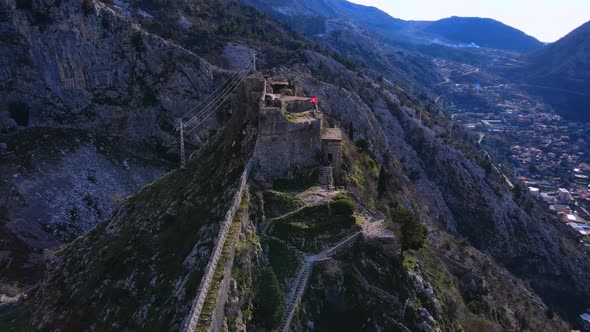 Old Fortress on Steep Mountain Top Against Town in Valley