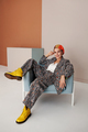 Hipster mature fashion woman in stylish suit with trousers and color print jacket sitting in chair  - PhotoDune Item for Sale