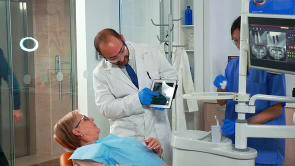 Dentist in Dental Office Examining Xray Image on Tablet