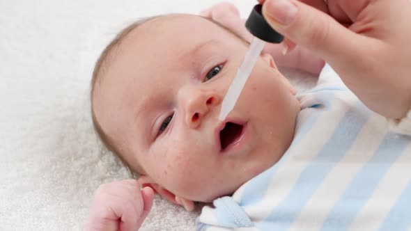 Closeup of Giving Vaccine To Newborn Baby Boy From Eyedropper or Syringe