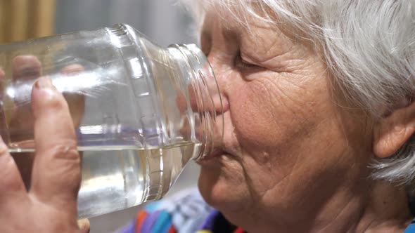 the Old Woman Drinks Water From a Glass Jar with Pleasure Relaxes and Becomes Very Happy