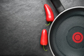Blank skillet with non-stick coated surface on the black slate with red peppers. Copy space. - PhotoDune Item for Sale