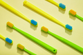 Different colors family toothbrushes, green and yellow on a yellow background. - PhotoDune Item for Sale