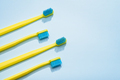 Modern yellow kids toothbrushes on a blue background. Copy space for your text, - PhotoDune Item for Sale