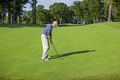 Golfer prepares to hit onto a green on a sunny afternoon - PhotoDune Item for Sale