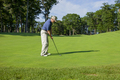 Golfer gets ready to hit onto a green on a sunny afternoon - PhotoDune Item for Sale
