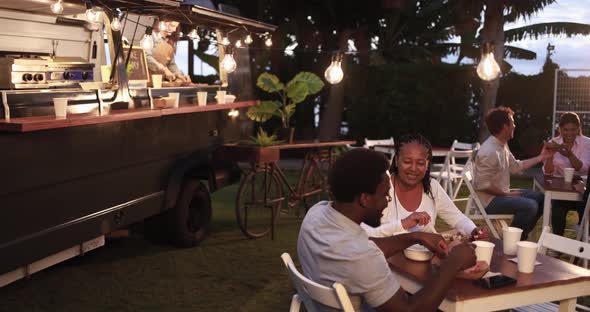 African mother and son eating food truck food outdoor at dinner time - Family and summer concept