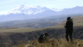 Tourists standing on a mountain top and looking on snow covered peaks. Creative. Picturesque valley - PhotoDune Item for Sale