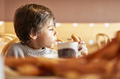 elementary age kid boy eating yummy churros into a hot chocolate mug - PhotoDune Item for Sale