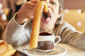 elementary age kid opening mouth to eat churro dripping hot chocolate - PhotoDune Item for Sale