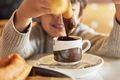 unrecognizable kid dipping churros in hot chocolate mug - PhotoDune Item for Sale