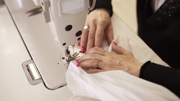 High Angle View of Female Hands with Colored Manicure in Process of Creating Wedding White Dress