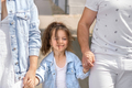 A young family leads a little curly-haired daughter by the hand along a city street - PhotoDune Item for Sale