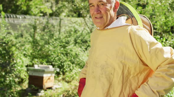 Portrait of smiling caucasian male beekeeper in protective clothing