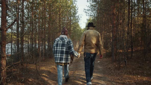 Couple Holding Hands while Walking with Dog in Forest