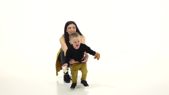 Girl with a Baby in His Hand Has Soft Toys. White Background. Slow Motion