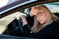 thoughtful middle-aged blonde in glasses sits behind the wheel of a car - PhotoDune Item for Sale