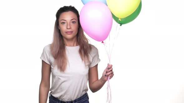 Portrait of Funny Woman Rejoicing and Dancing with Colorful Ballons in Her Hands at Party Over White