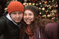 Close up positive couple in love wearing hats and winter clothes at christmas tree background - PhotoDune Item for Sale
