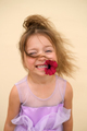 Beautiful curly-haired girl with petunia flower in her mouth smiles sweetly - PhotoDune Item for Sale