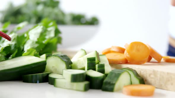 Mid-section of woman cutting vegetables on chopping board