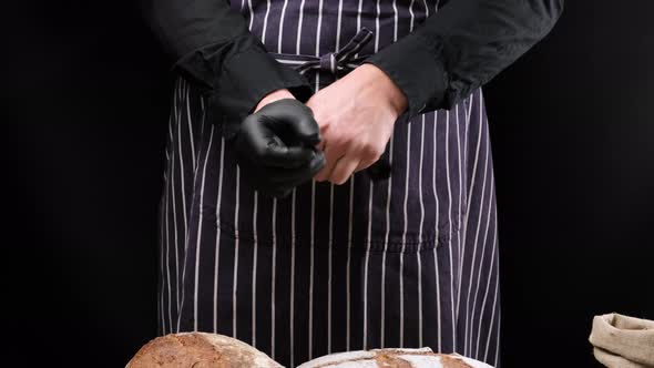chef in black shirt and apron puts black latex gloves on his hands
