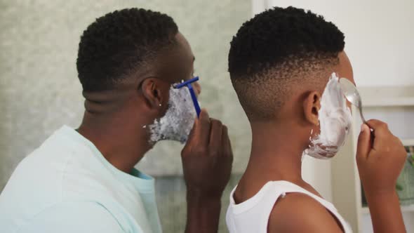 African american father and son shaving together