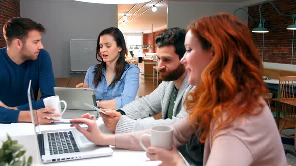 Business executives discussing over digital tablet and laptop