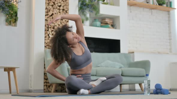 Young African Woman Doing Stretches on Yoga Mat at Home