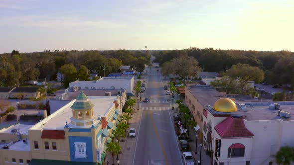 Backwards Aerial Pan of Shops and Restaurants on the Main Road of a Small Town