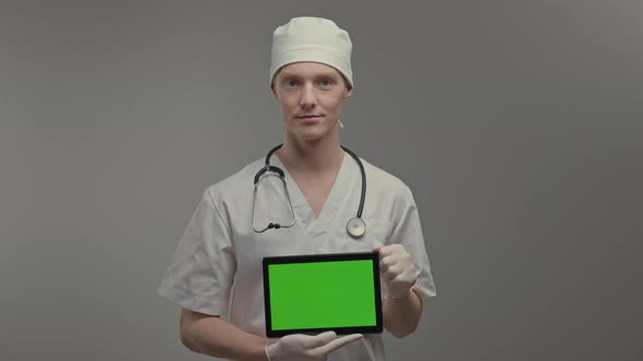 Young Doctor In Medical Gown And Gloves He Holds Tablet