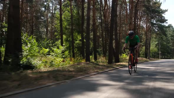 Triathlon Training. Cyclist Riding on Road Bike in City Park. Slow Motion